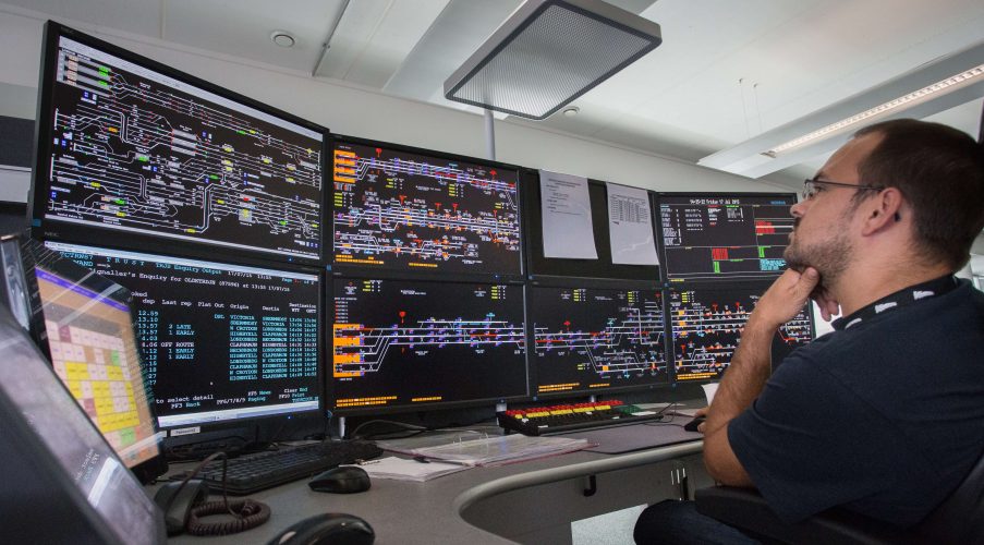 A signaller working with digital signalling screens at Three Bridges rail operating centre (ROC)