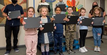 School children and teachers holding laptops donated by Network Rail