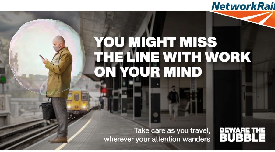 站立在黄色线前面的人，他的手机分散了他的手机作为火车方法。海报有“你可能会错过那条线，你的思想工作。随着你的旅行，在你的注意力奇迹时照顾”