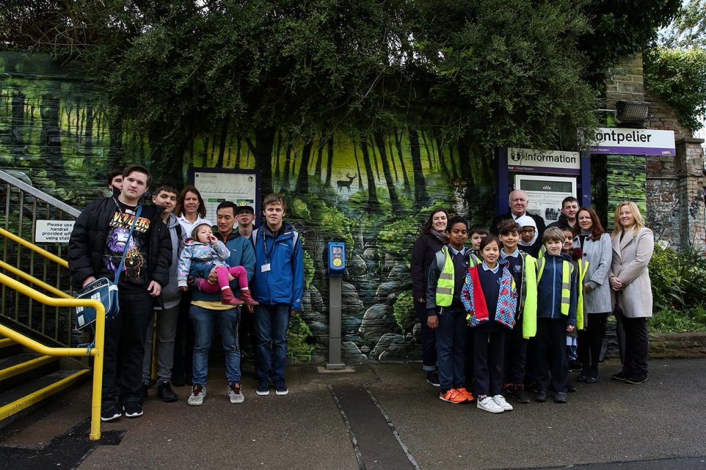 在蒙彼利埃车站，大人和孩子们站在社区铁路的壁画前亚搏真人