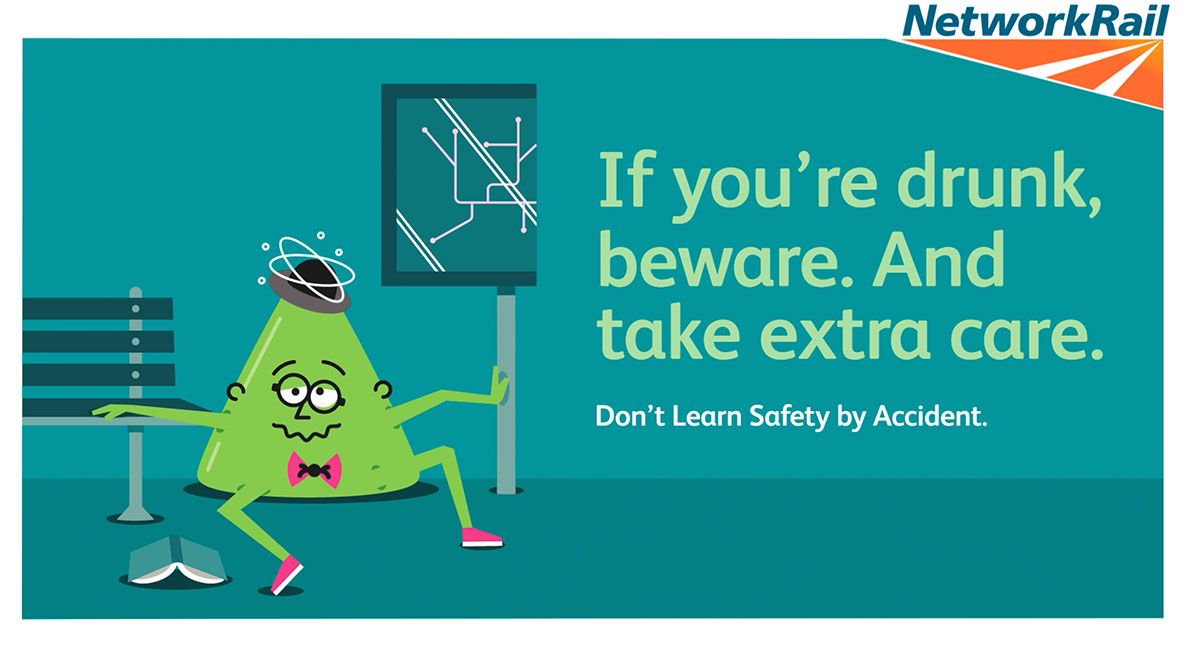 一个卡通人物的海报坐在火车站的地板上。副本上写着“如果你喝醉了，当心。多加小心。“不要误学安全”